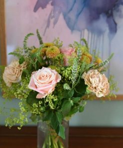 Buket med lyserøde blomster og et maleri i baggrunden