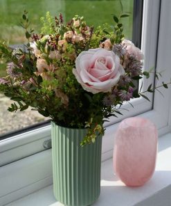 Buket med lyserøde roser, og andre lyserøde blomster som astrantia, limolium, leukøjer og forskelligt grønt i vindueskarm