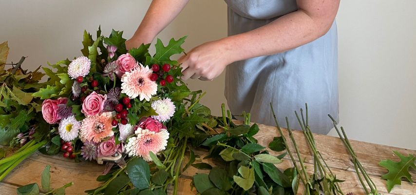 person binder en buket med røde og lyserøde blomster