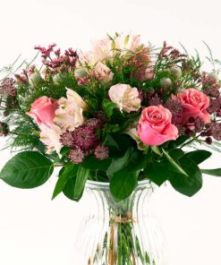 Luftig buket i rosa nuancer, som står i en gennemsigtig glasvase.