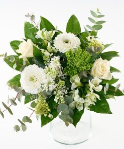 En lav buket bumdet af hvide blomster; roser, gerbera, chrysanthemum, syrener, alstroemeria og grønt.