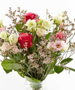 En luftig buket bundet af blomster i rødlige, lyserøde og hvide nauncer.