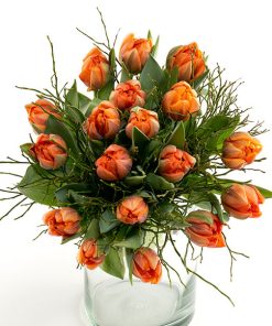 Buket orange tulipaner i en gennemsigtig glasvase.