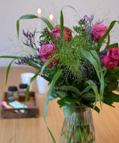 Buket af pink roser og små lilla blomster på træbord