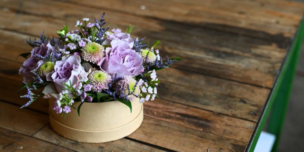 Blomsteræske i lilla farver på bordplade af træ