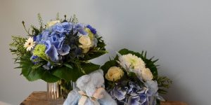 Mor-barn buket i blå og hvide. Foran sidder en lyseblå bamse.