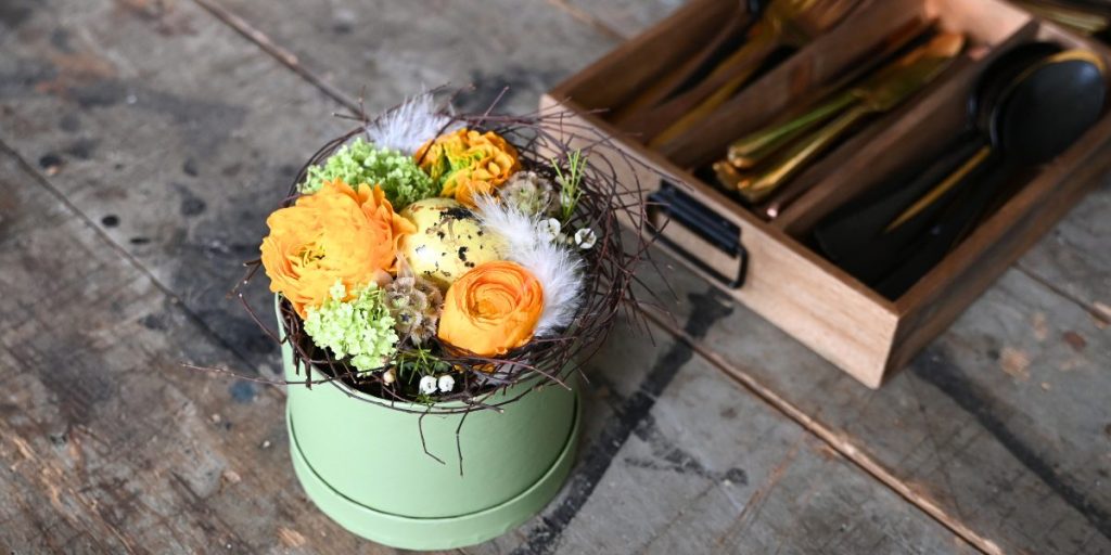 Grøn blomsteræske med gule blomster på træbord