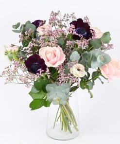 Luftig buket i rosa og lyserøde nuancer, som står i en gennemsigtig glasvase.