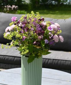 Sød lilla buket står på et havebord